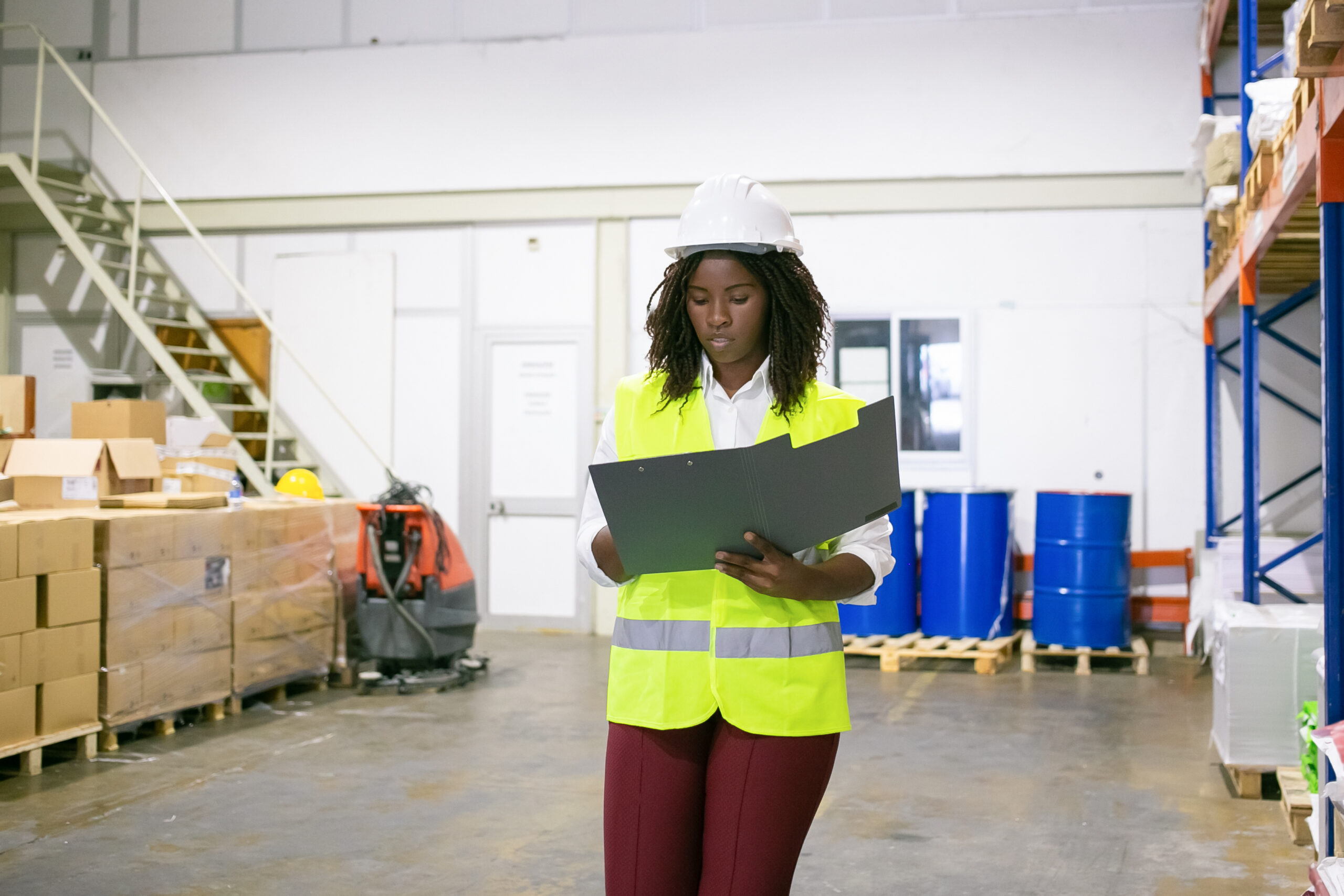 focused female logistic employee in hardhat and safety vest